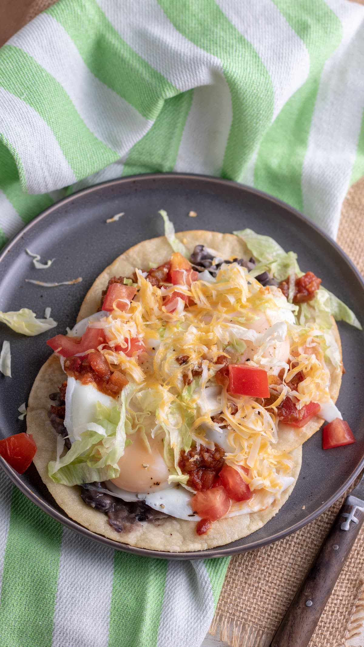 Huevos rancheros on grey plate with colorful toppings.