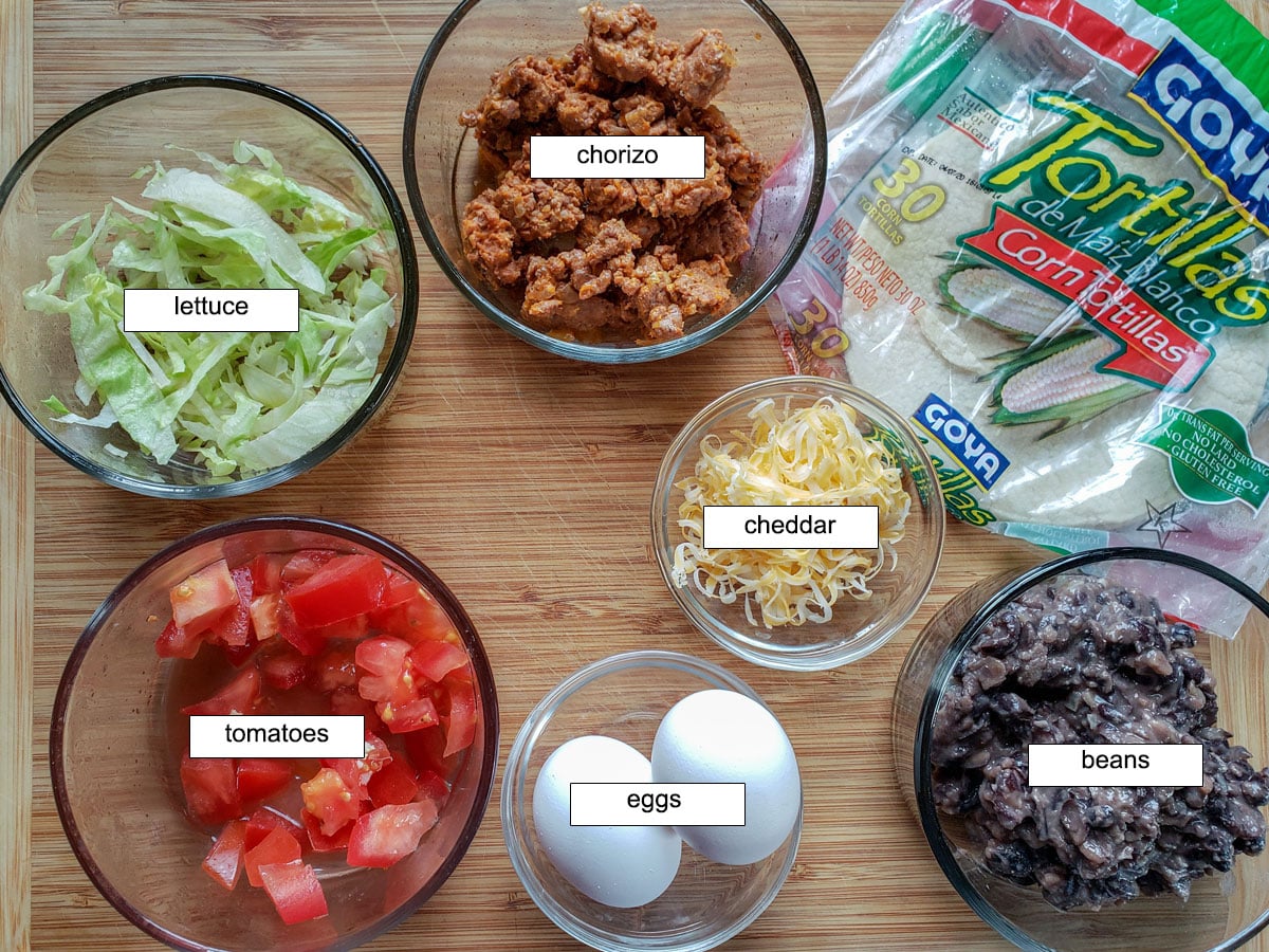 Ingredients, chorizo, tortillas, lettuce, tomatoes, cheese, eggs, beans.