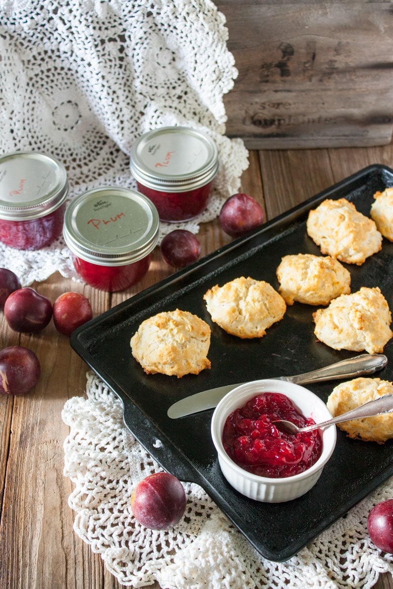 plum jam in white bowl on antiques baking sheet with biscuits and antiques doily plum jam in white bowl on antiques baking sheet with biscuits and antique doily