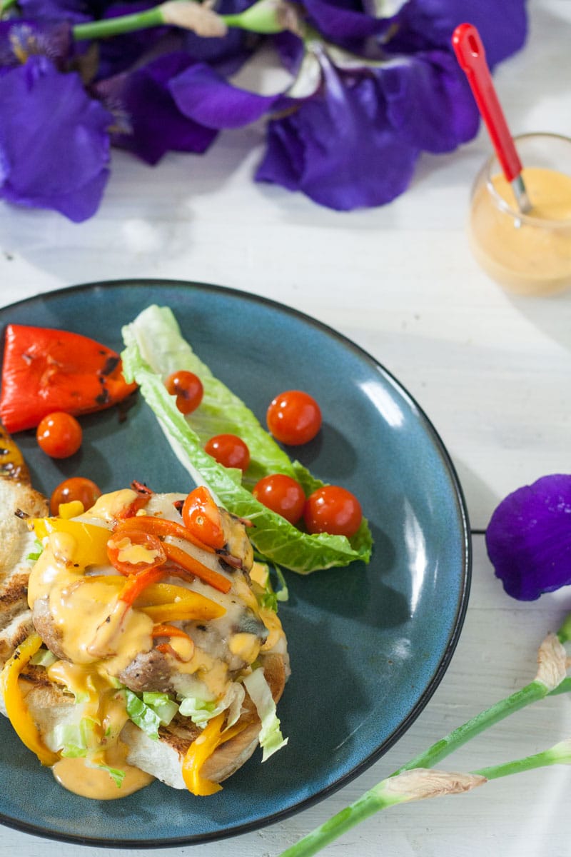 dressed turkey burger on a bun loaded with sauce, cheese, peppers, onions and tomaotes