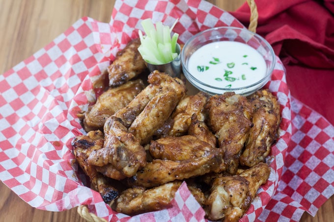 Chicken wings in basket with dipping sauce and celery.
