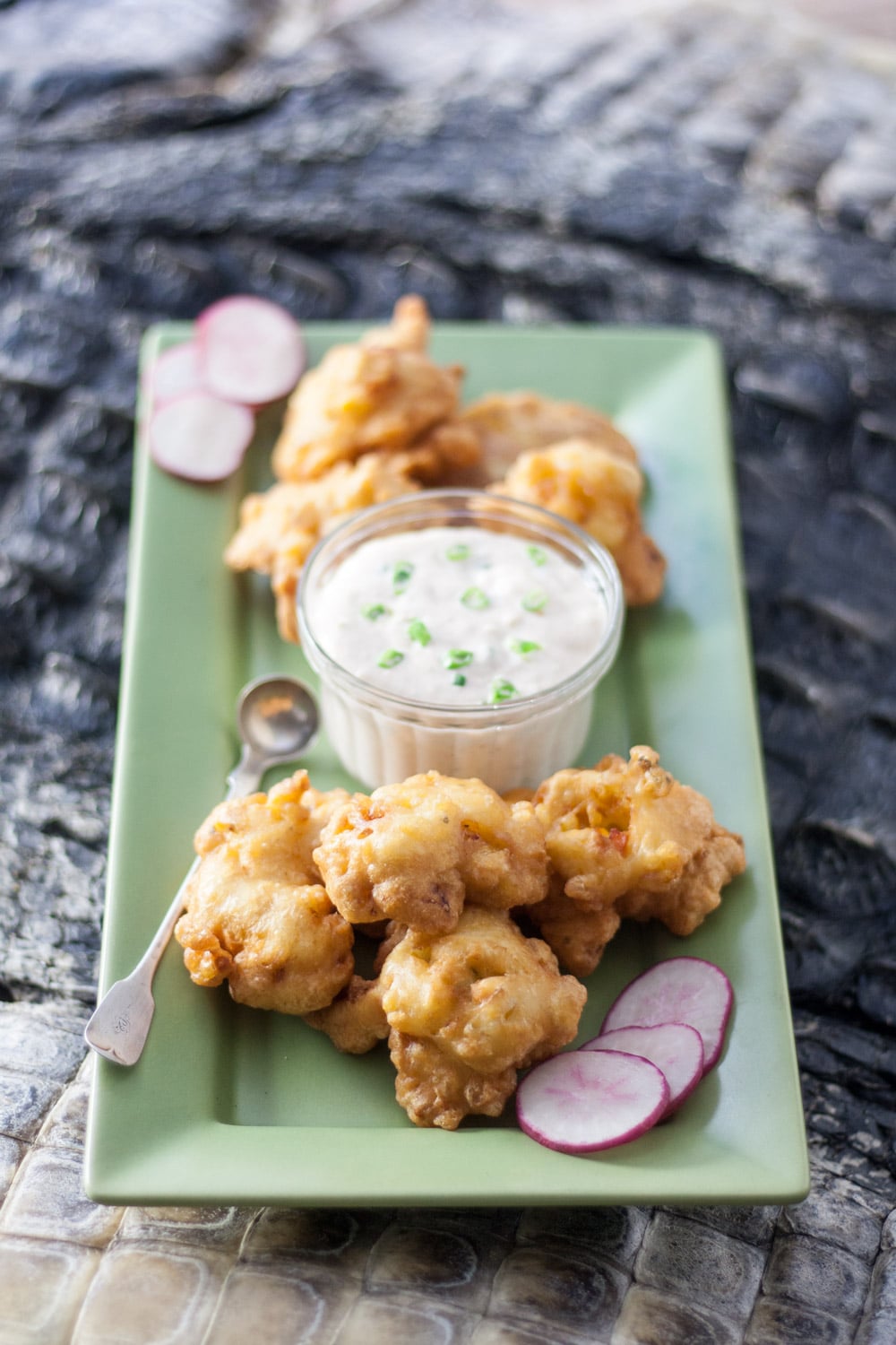 alligator hush puppies on green plate with alligator skin board in background