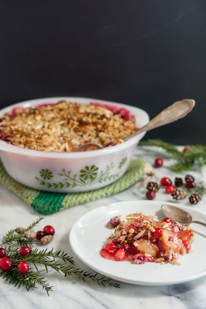 Apple cranberry crisp on white plate with spoon.