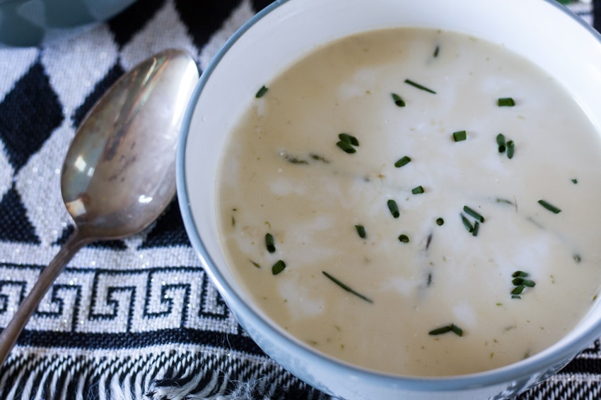 Creamy asparagus soup in blue bowl witb black and white placemat