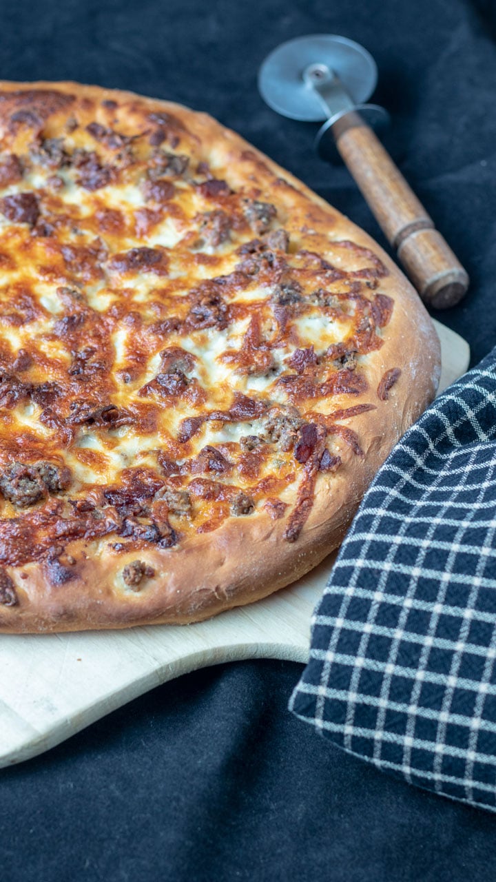 Whole pizza on wooden peel. Whole pizza on wooden peel.