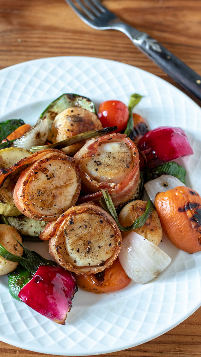 skewers of scallops and vegetables on bamboo cutting board