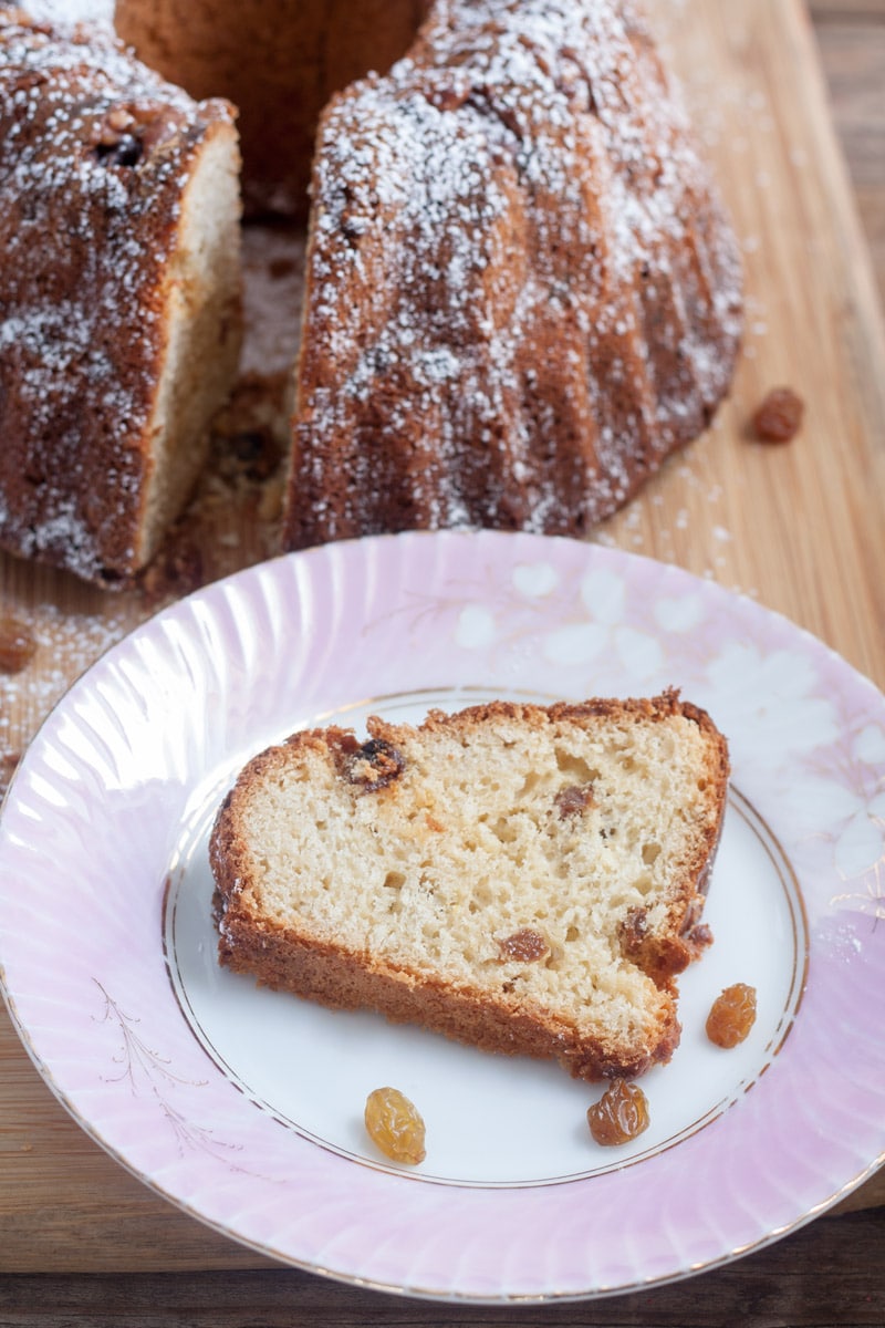 slice of gugelhopf on antique pink plate with whole bread in the background