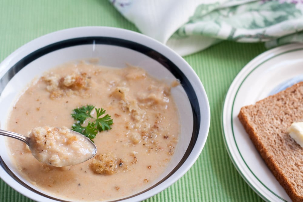 Soup in white bowl with crouton and parsley garnish