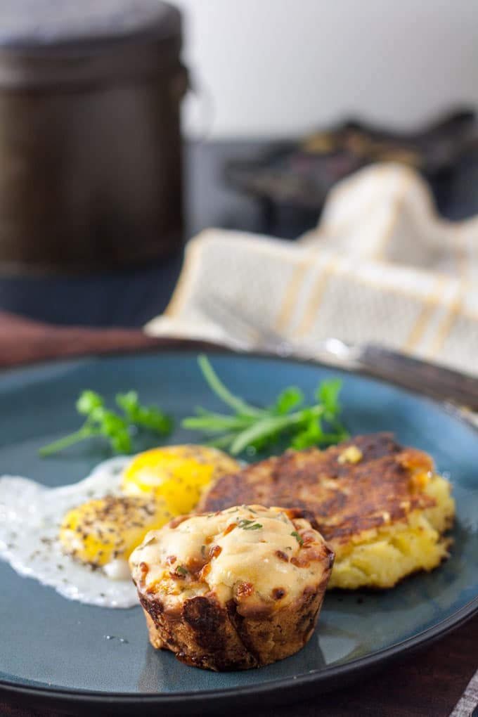 Muffin on plate with potato pancake and eggs.