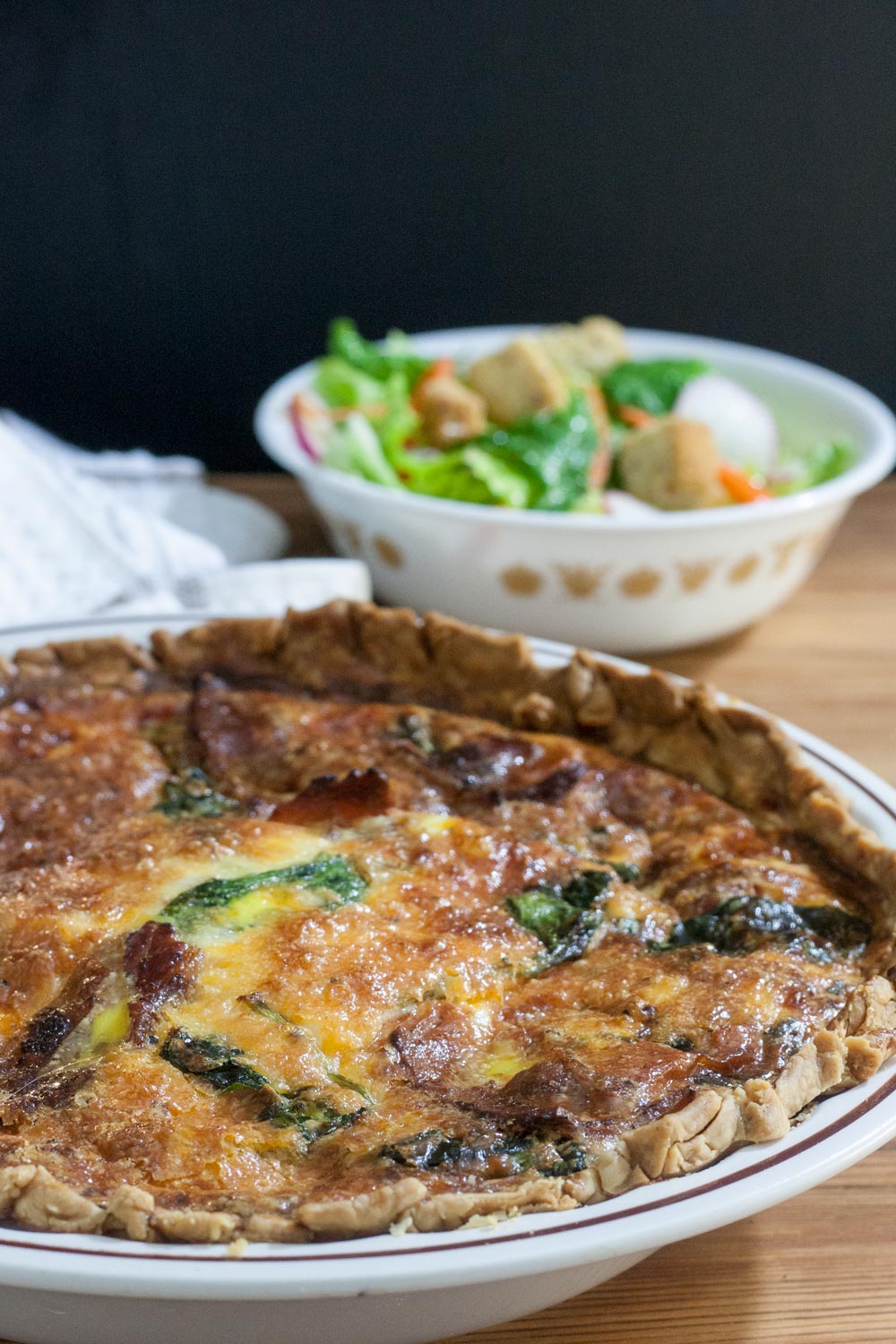 close up of whole quiche with spinach, chicken, bacon and cheese