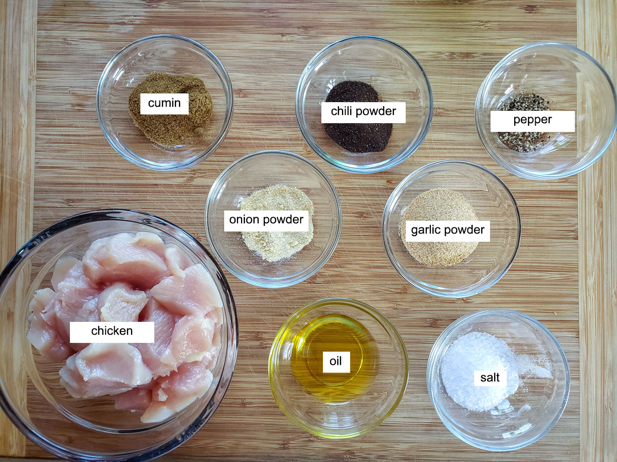 Ingredients for chicken nachos, Chicken, oil and spices on bamboo board.
