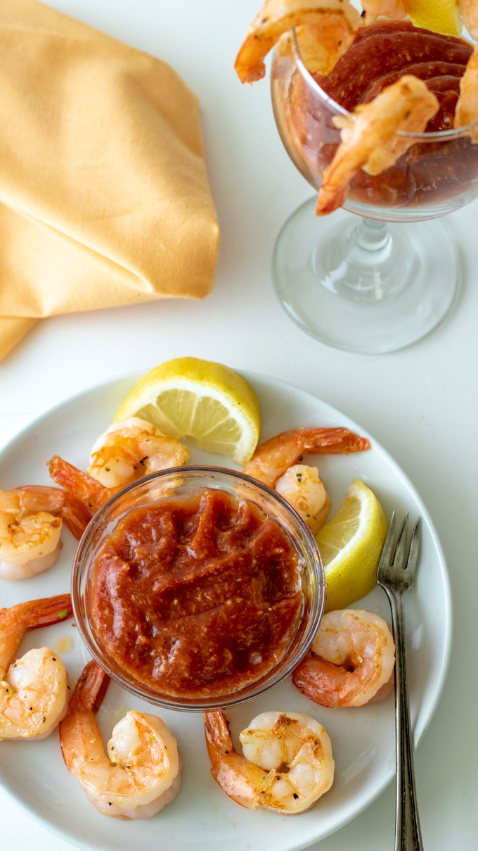 cocktail sauce and shrimp arranged on small white plate