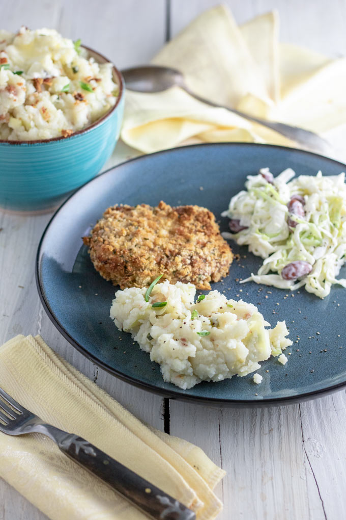 colcannon served with breaded pork chop and coleslaw on blue plate