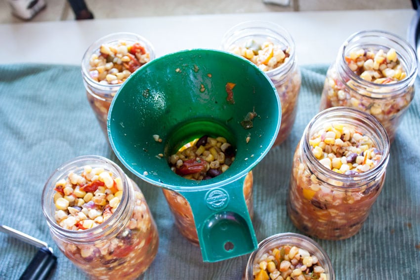 filling corn and black bean salsa in jars