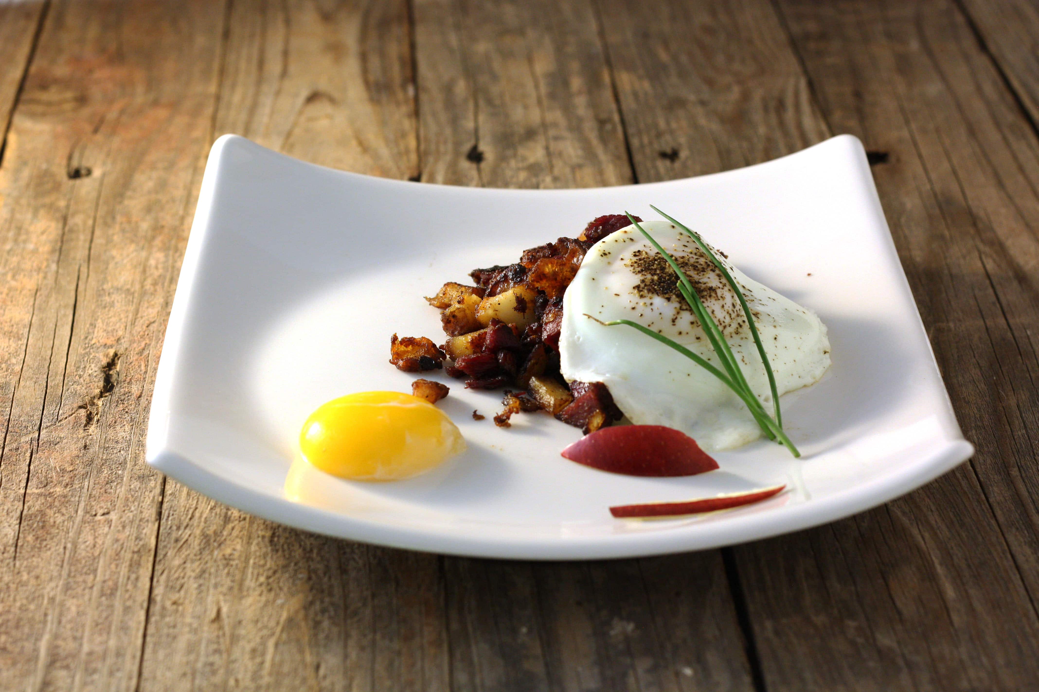 Corned Venison and potato hash topped with egg on white plate