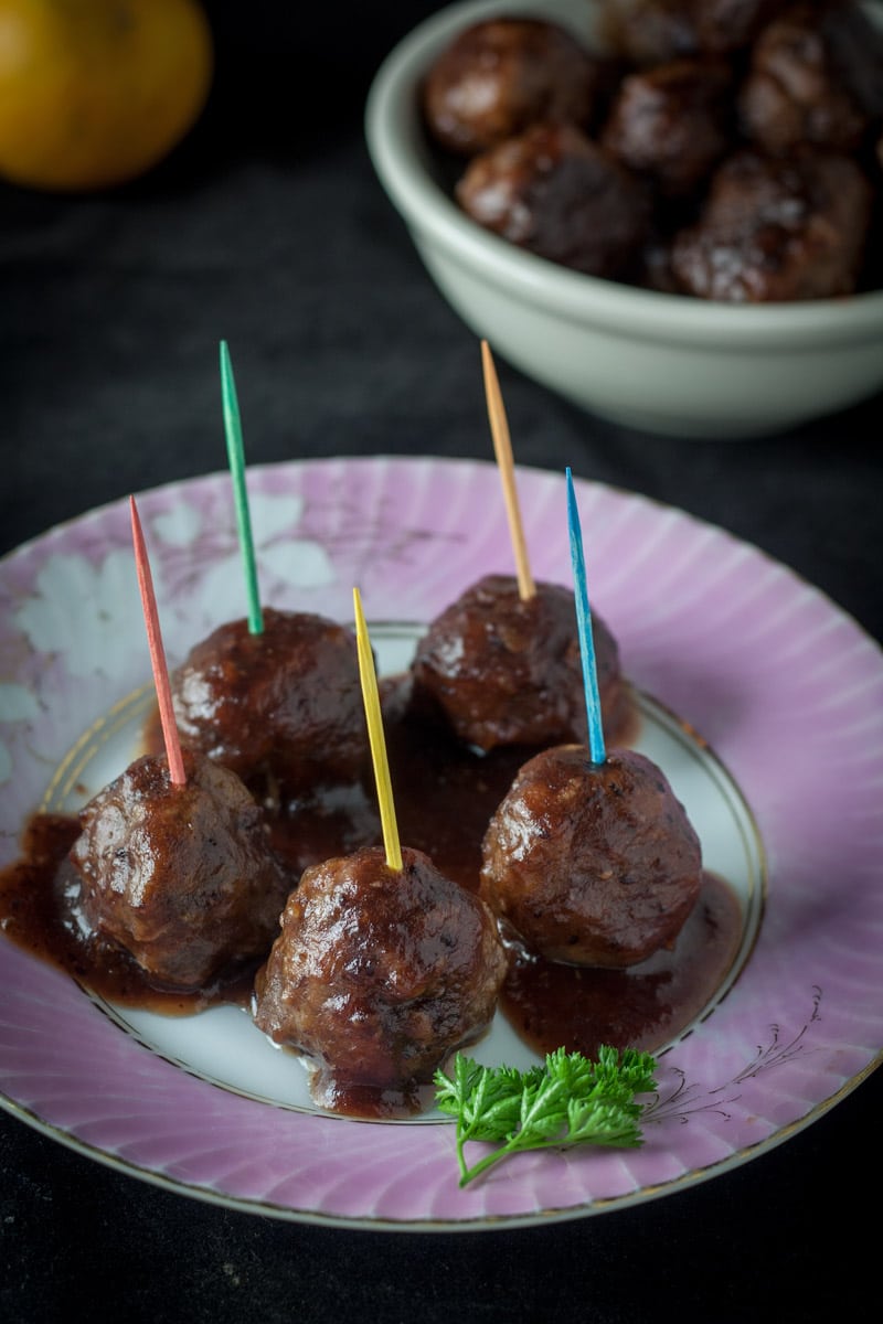Cranberry orange meatballs with colored toothpicks on pink antique plate