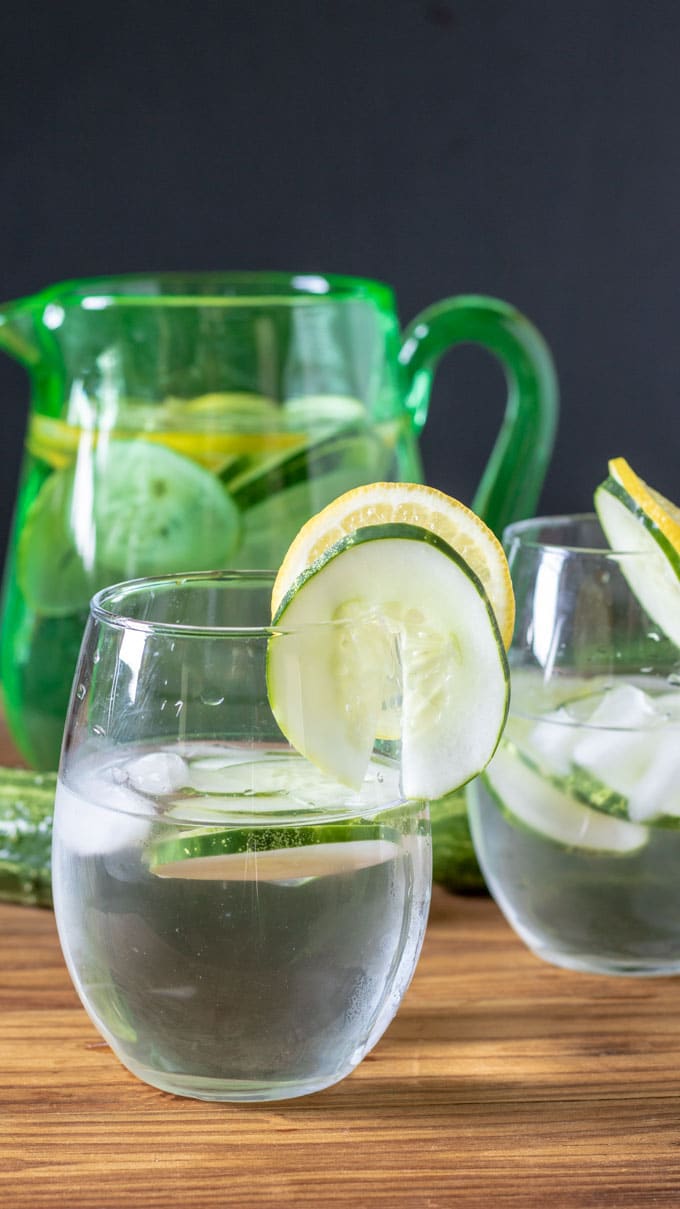 green pitcher with 2 clear glasses cucumber water