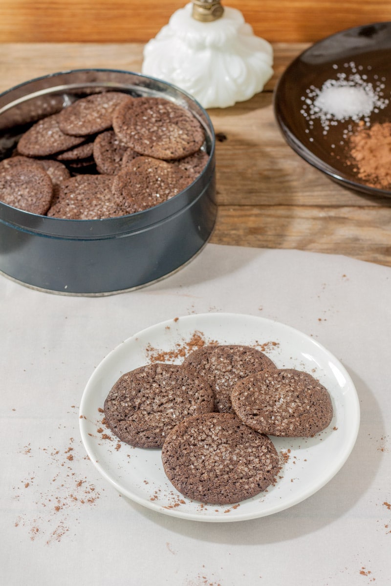 cookies on white plate with cookie tin filled with cookies chocolate cookies on white plate with cookie tin filled with cookies in background