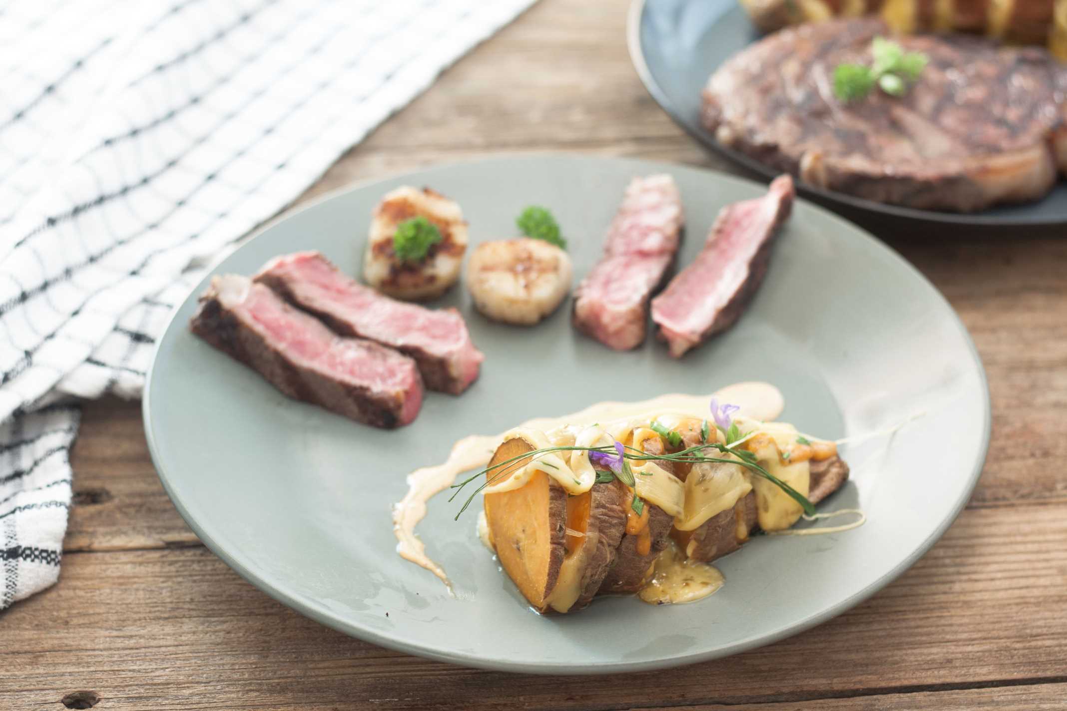 Hasselbeck Style Sweet Potatoes with beef and scallops on green plate