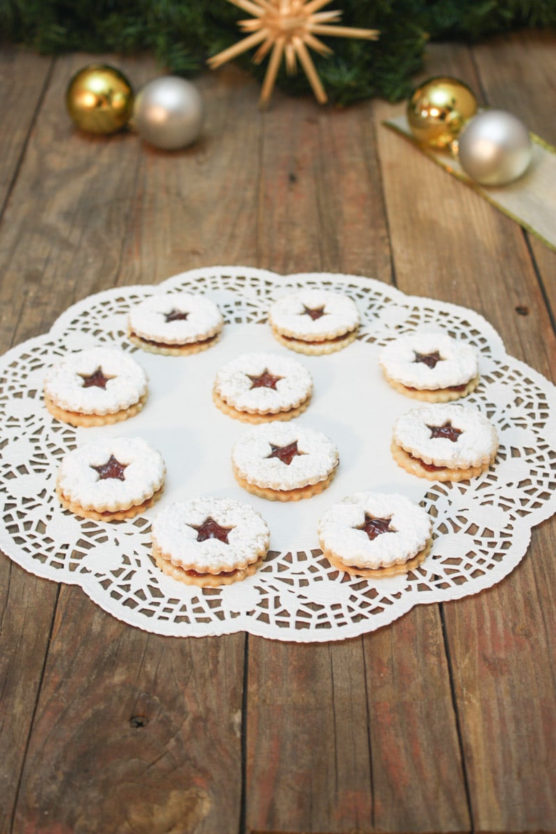 powdered sugar sprinkled spitzbuben cookies on doily.