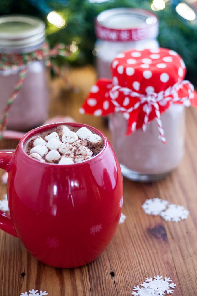 Large red mug filled with hot cocoa topped with marshmallows and shaved chocolate