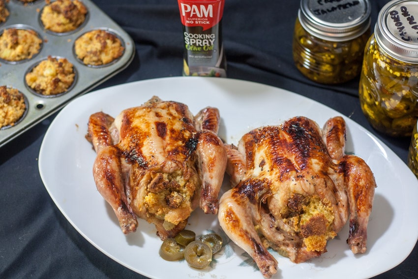 2 game hens on white platter with canned jalapeños and stuffin muffins