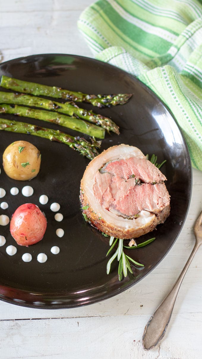 grilled asparagus with lamb loin on black plate