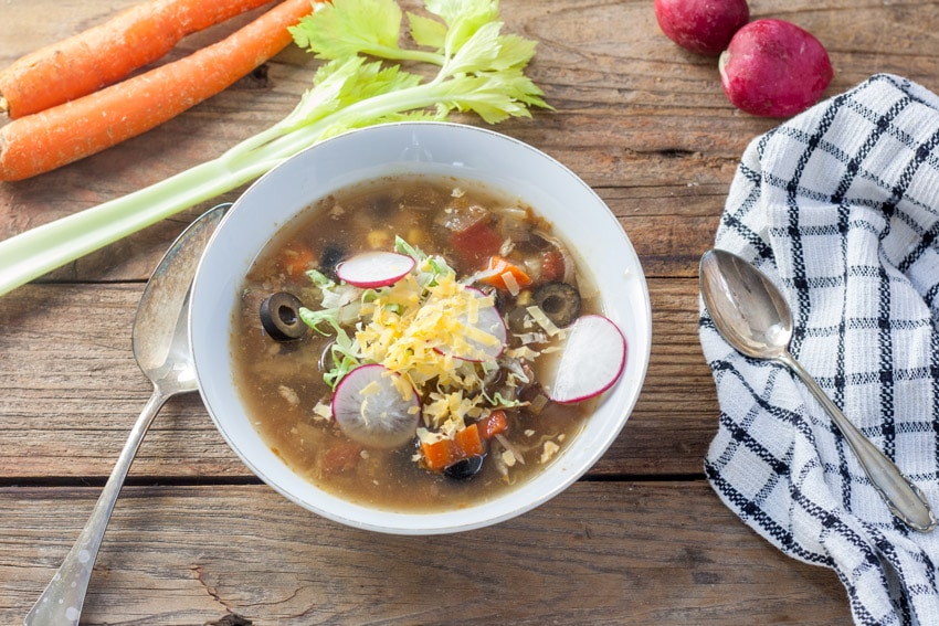 mexican turkey soup in white bowl with a white checked tea towel