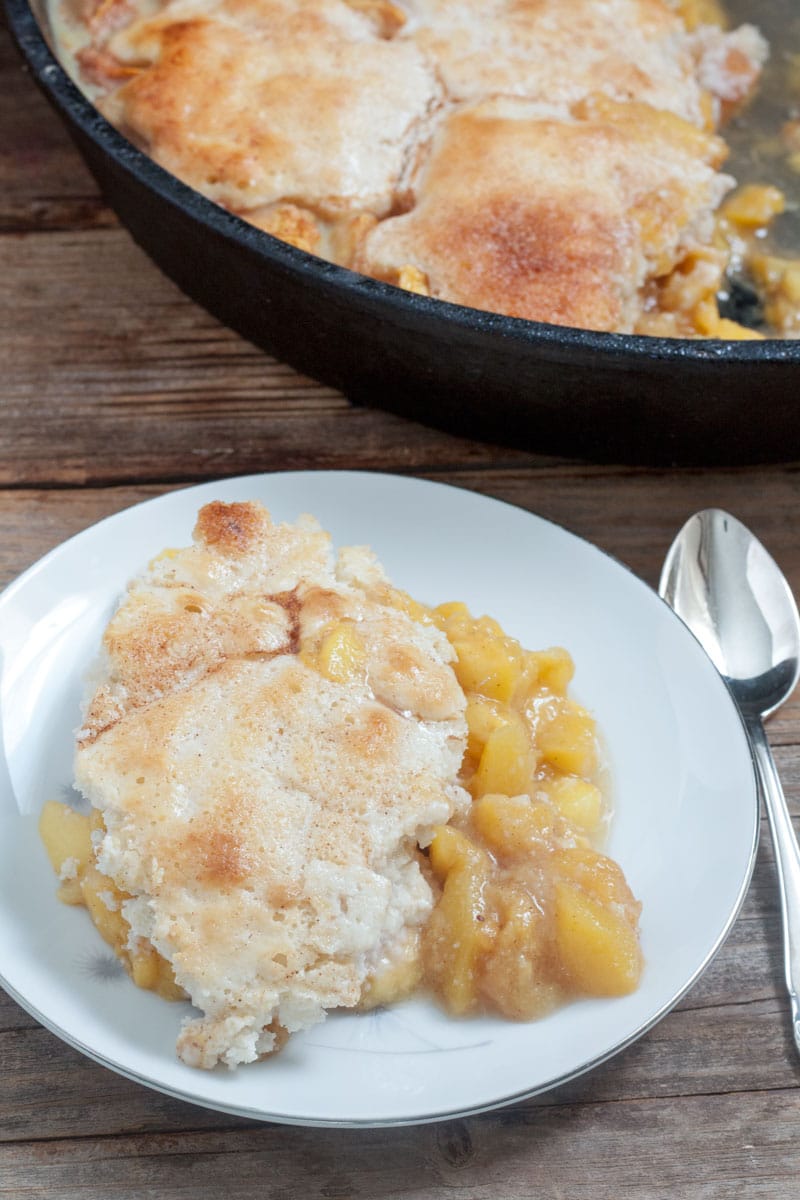Spoon dipping out peach cobbler.