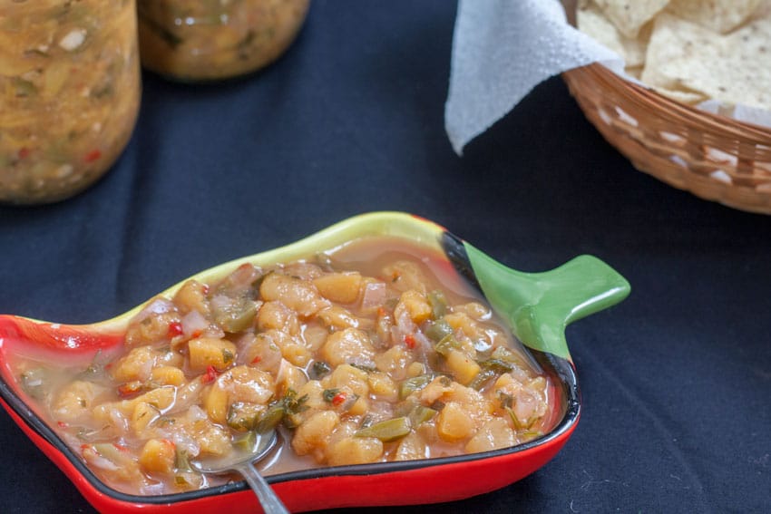 Peach Salsa in chili bowl with basket of tortilla chips.