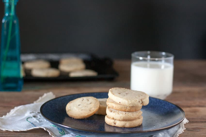 pecan sandies on dark blue plate with a glass of milk