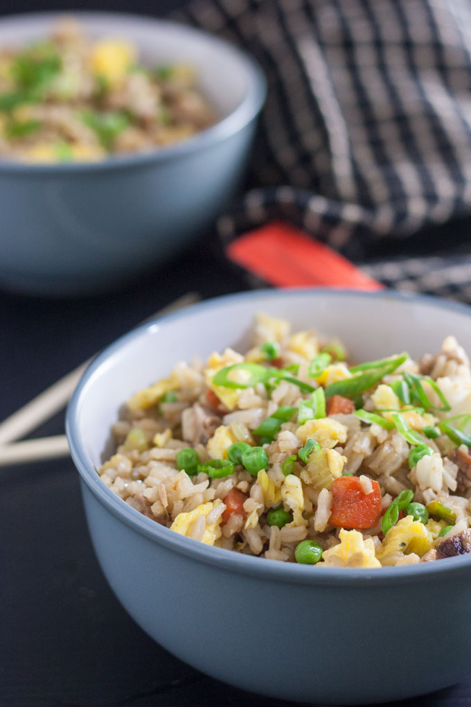 2 bowls pork fried rice on black background with chopsticks