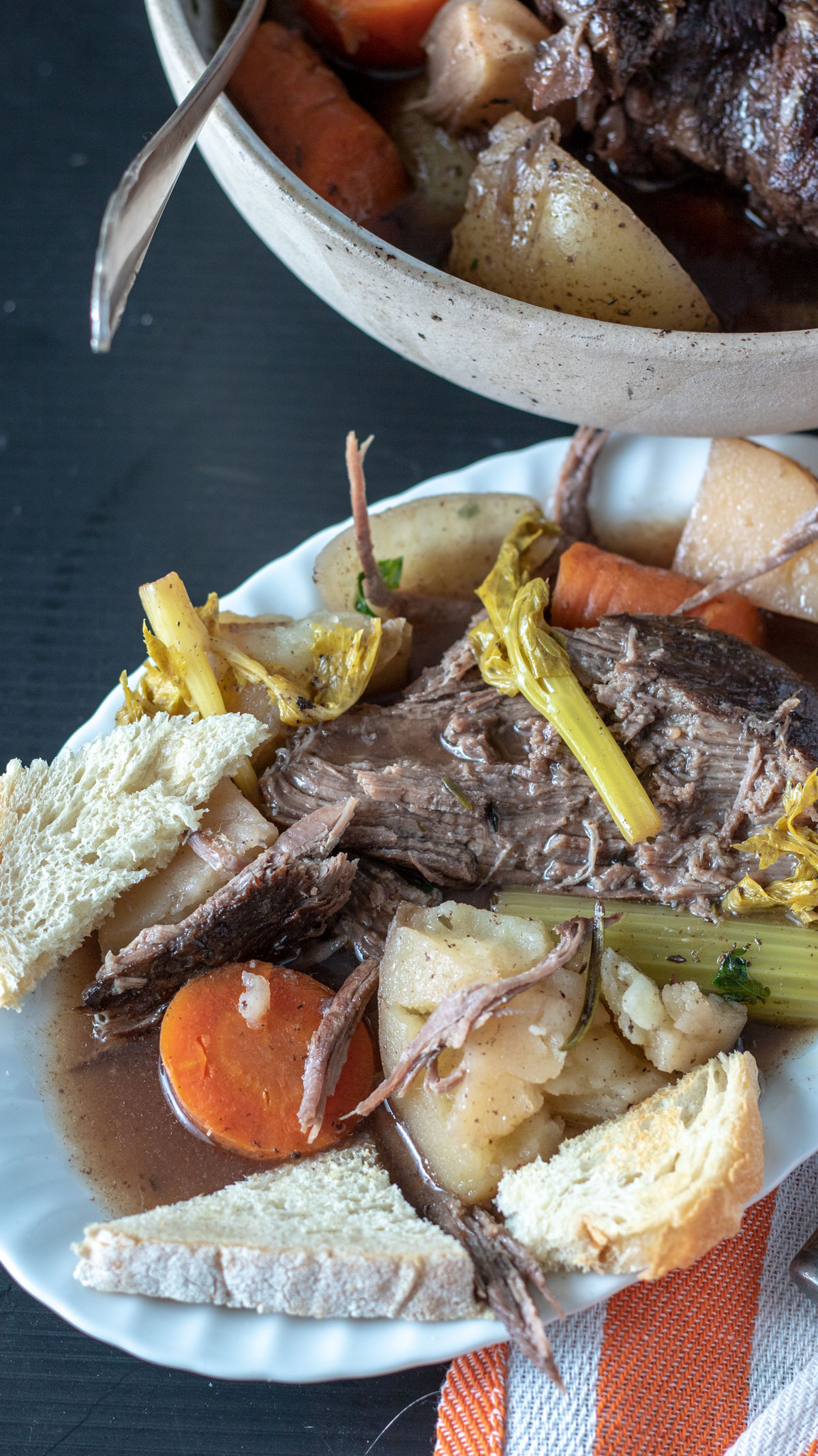 Serving of pot roast on white plate topped with vegetables with toast points.