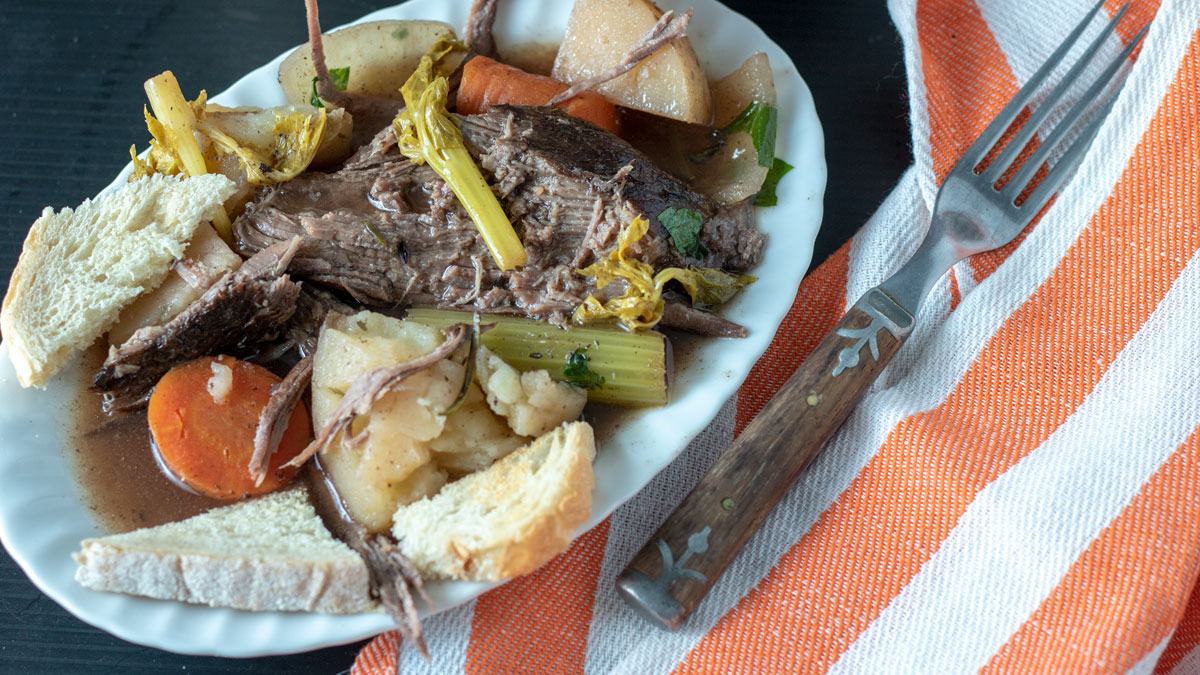 Serving of pot roast on white plate.