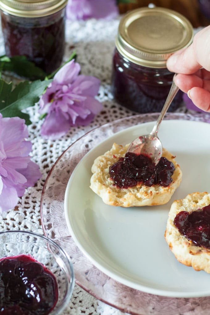 hand spreading blackberry jam on English muffins
