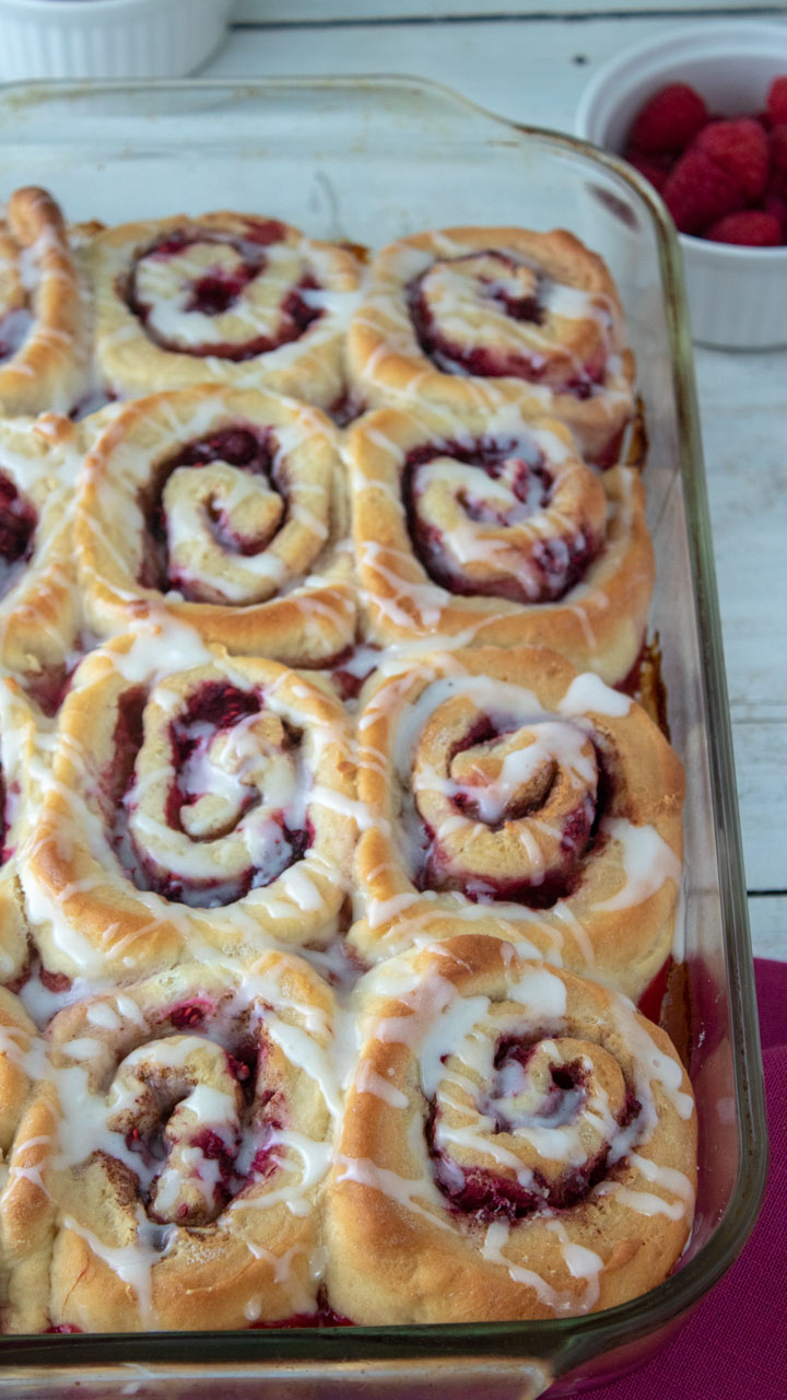 Colorful raspberry cinnamon rolls in baking pan.