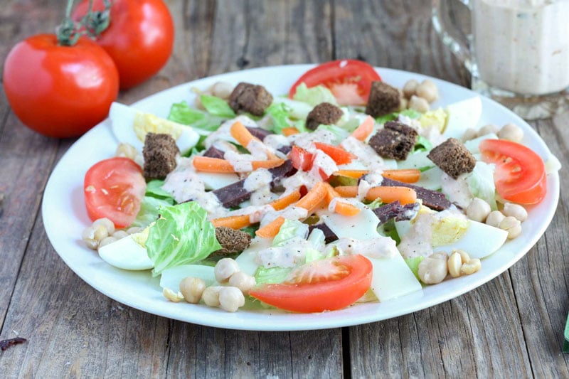 Dinner salad on ehite plate with corned venison, swiss cheese, tomato & boiled egg.
