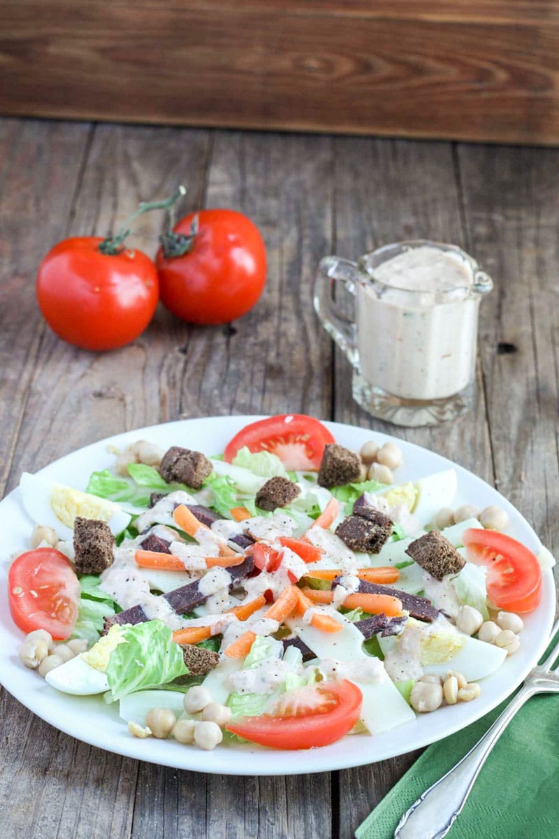 Reuben Dinner Salad on white plate with pitcher of thousand island dressing