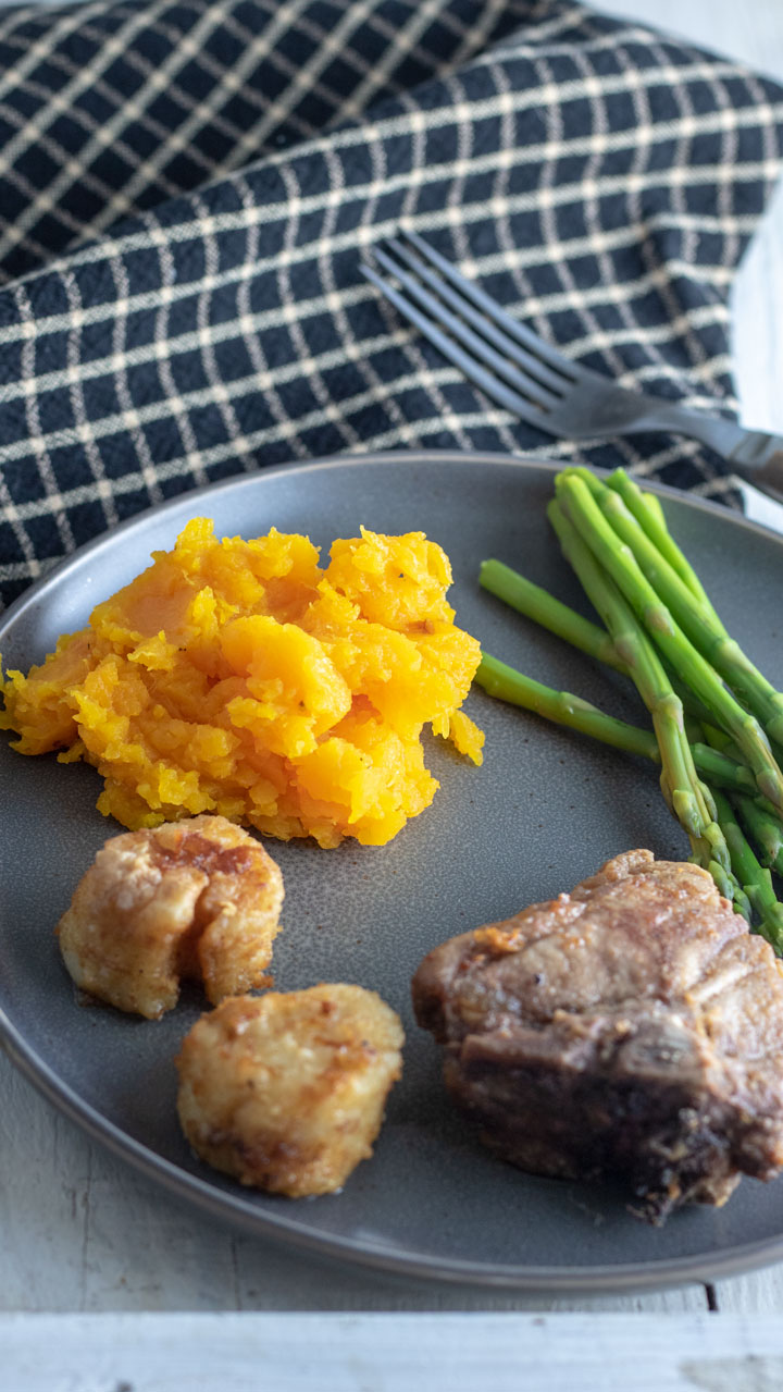 Mashed butternut on dinner plate with lamb and asparagus.