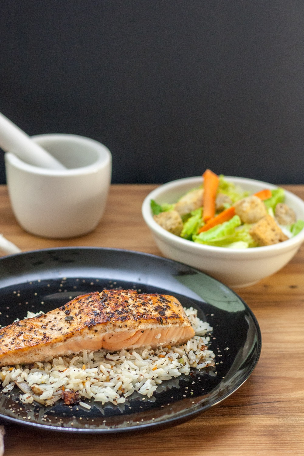 salmon filet on a bed of rice and a black plate