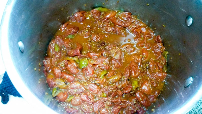 Roasted heirloom cherry tomatoes in pot to cook down liquid.