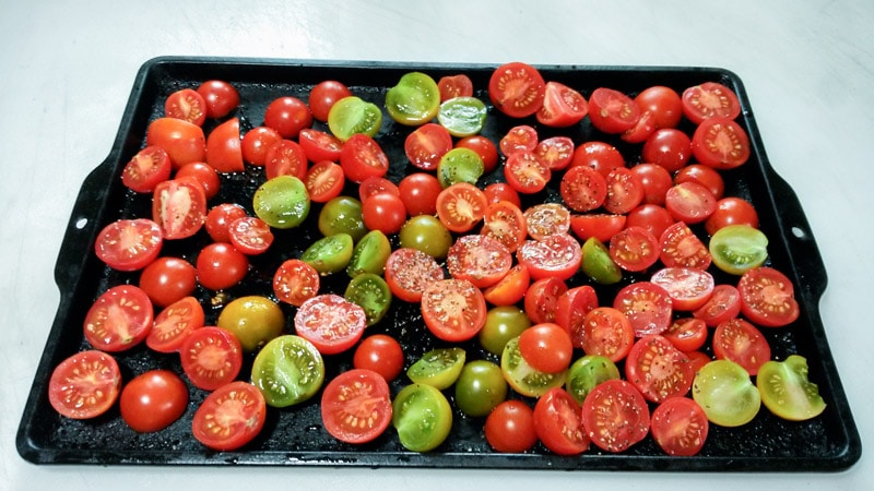 Fresh cherry tomatoes sliced in half, on roasting pan