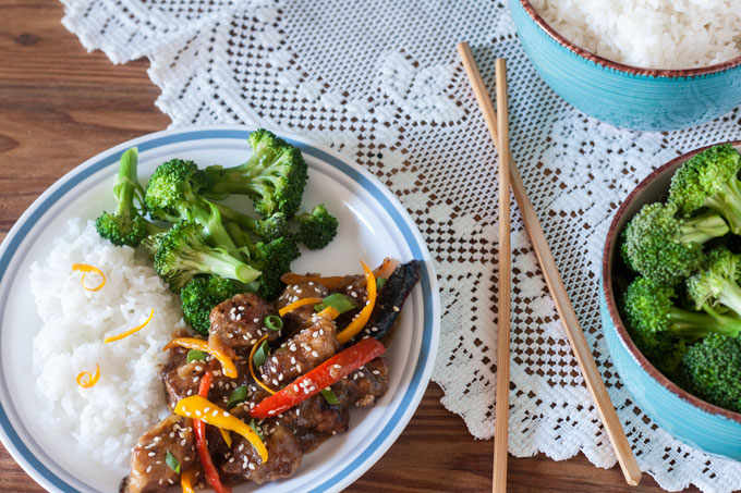 Sesame Orange Chicken stir fry on white plate with stir fried peppers