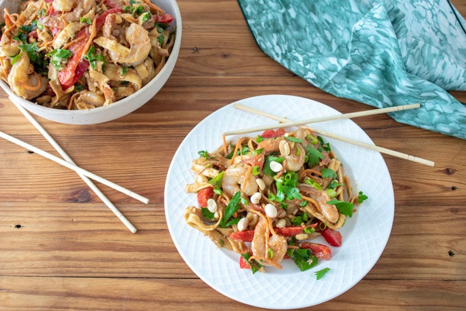 white plate with noodles, shrimp and veges