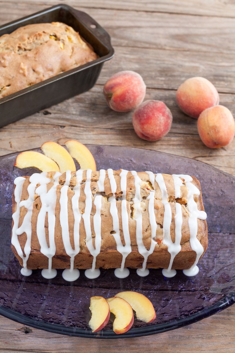 Glaze dripping from the sides of Peach Pecan Quick Bread 