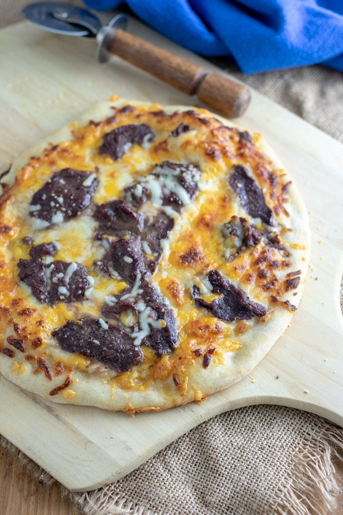 steak and cheese pizza with wooden pizza cutter