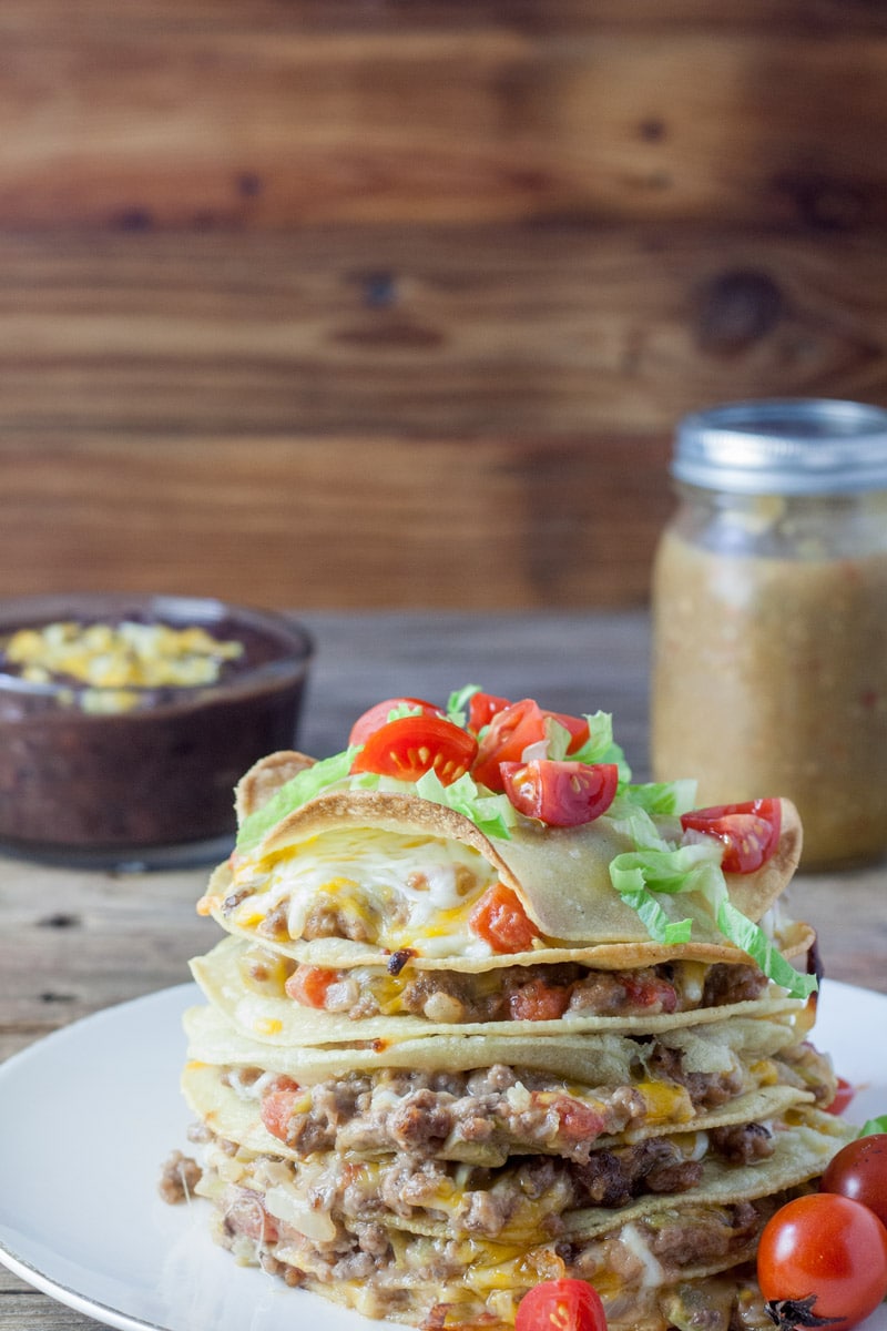 Tortillas, beef and melted cheese stacked on top of each other in layers.
