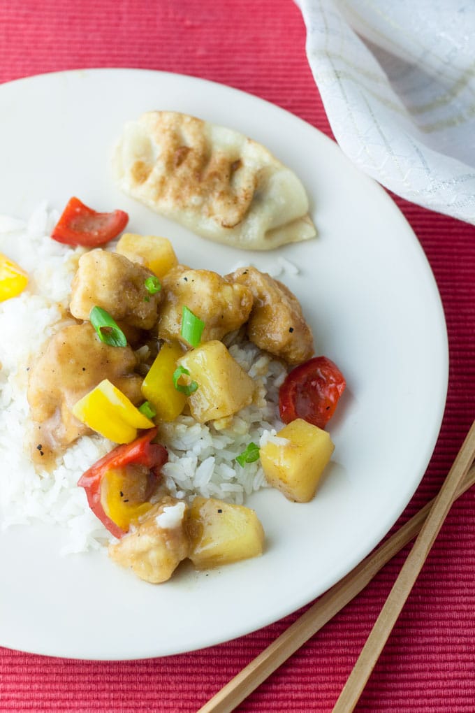 sweet and sour chicken with potsticker on red placemat sweet and sour chicken with potsticker on red placemat