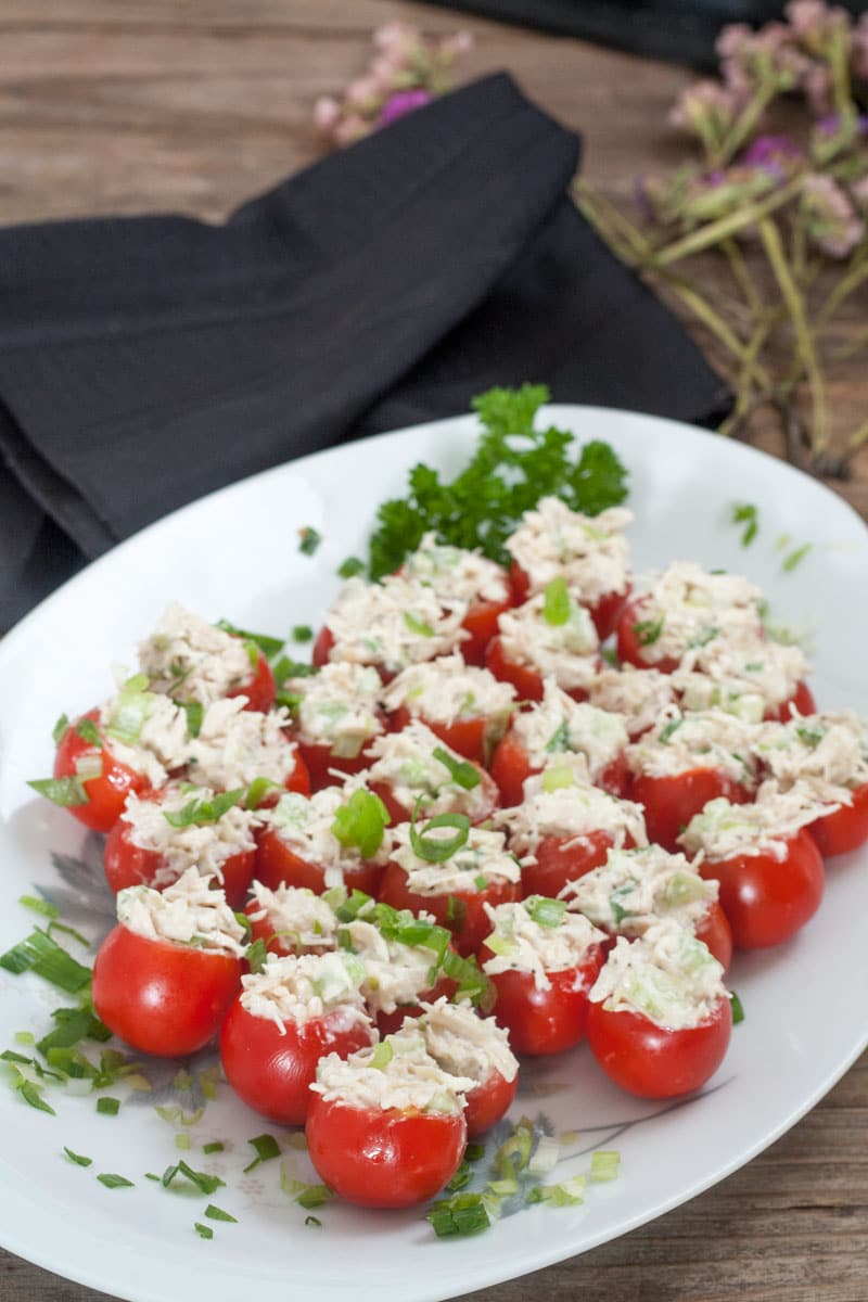Chicken Stuffed Tomato Bites on white plate with green onion garnish.