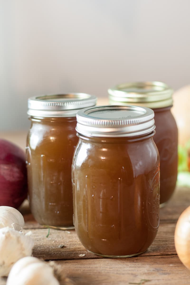 Jarred vegetable stock with mixed vegetables in background